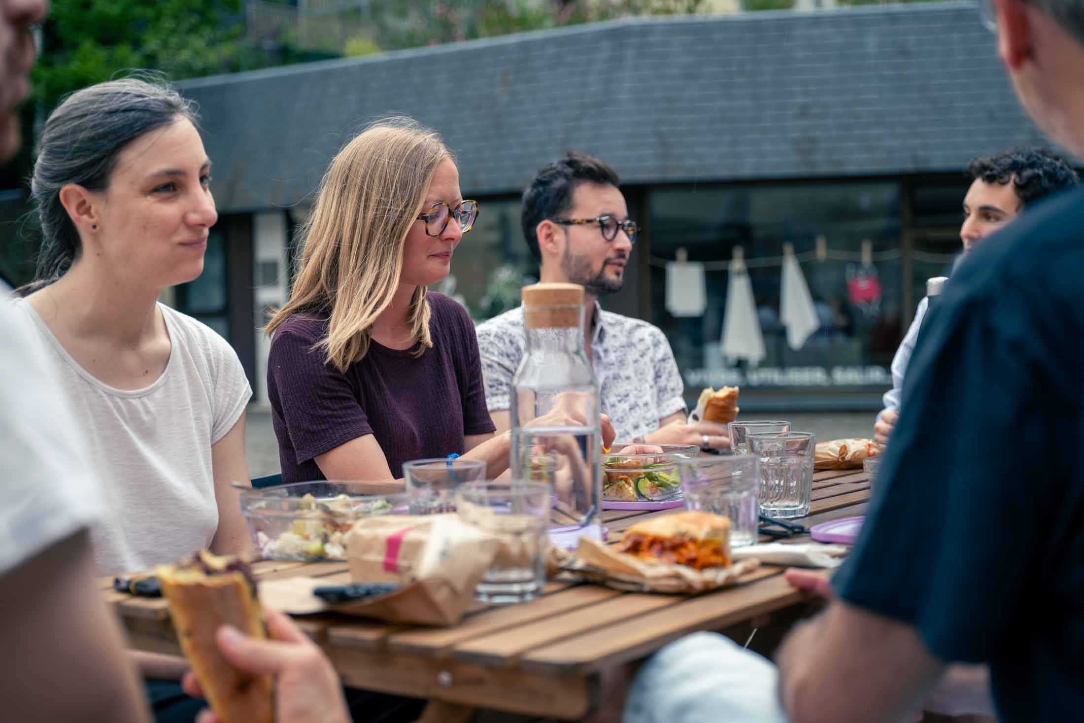 Repas partagé en extérieur entre coworkers devant la maison, à deux pas de la place des Lices