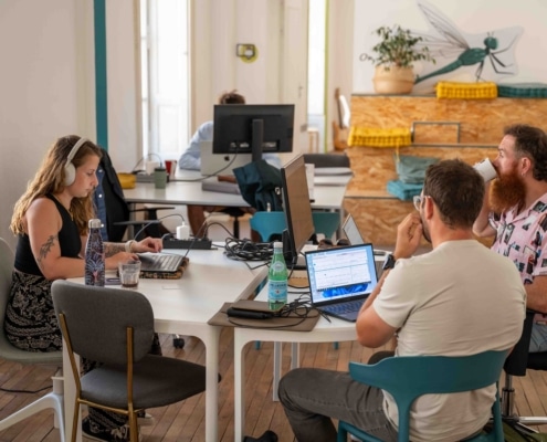 Photo d'un coworking ouvert et lumineux. Des personnes travaillent sur des écrans d'ordinateurs en buvant un café.