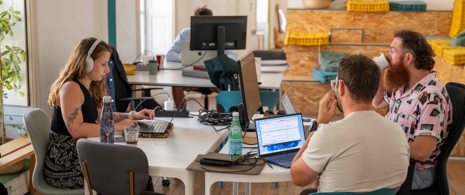 Photo d'un espace de travail ouvert et lumineux. Des personnes travaillent avec des écrans d'ordinateurs et boivent du café.